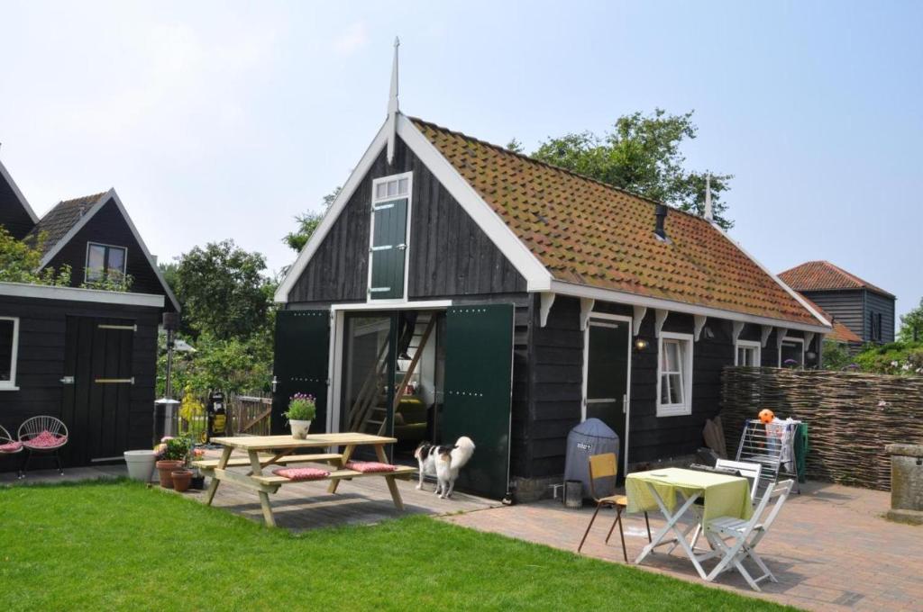 a black house with a dog standing outside of it at Tiny house Watergang in Watergang