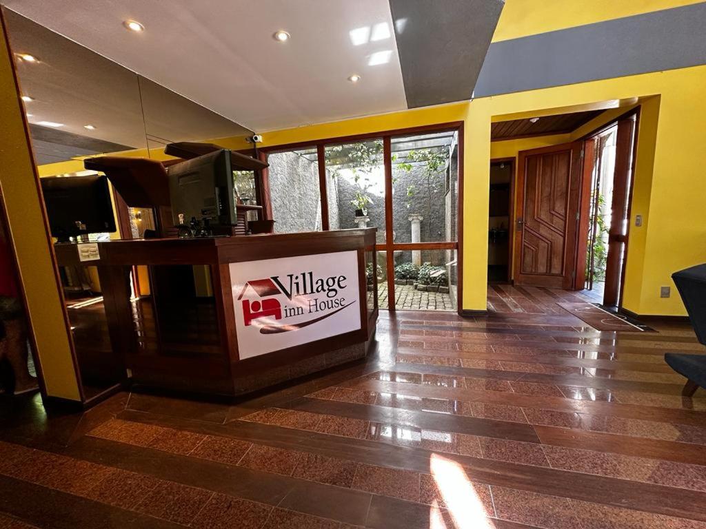 彼得罗波利斯Village Hostel的带电视的客厅和铺有地板的大堂。