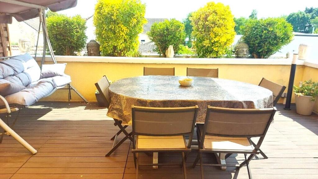 een tafel en stoelen op een patio met een tafel en een bank bij Appartement Familial pour 6 adultes et 5 enfants à 10 min de Disney in Bailly-Romainvilliers