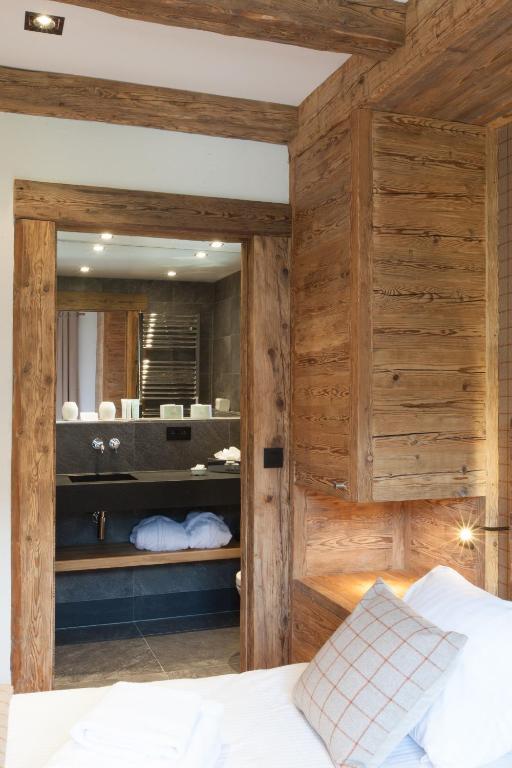 a bedroom with wooden walls and a bed with a mirror at Au Coin Du Feu in Megève