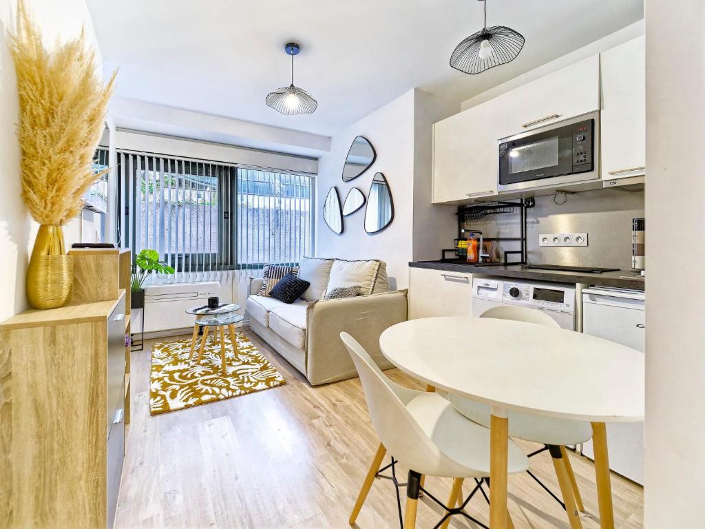 une cuisine et un salon avec une table et des chaises blanches dans l'établissement Magnifique T2 neuf - résidence neuf- Hyper central, à Nice