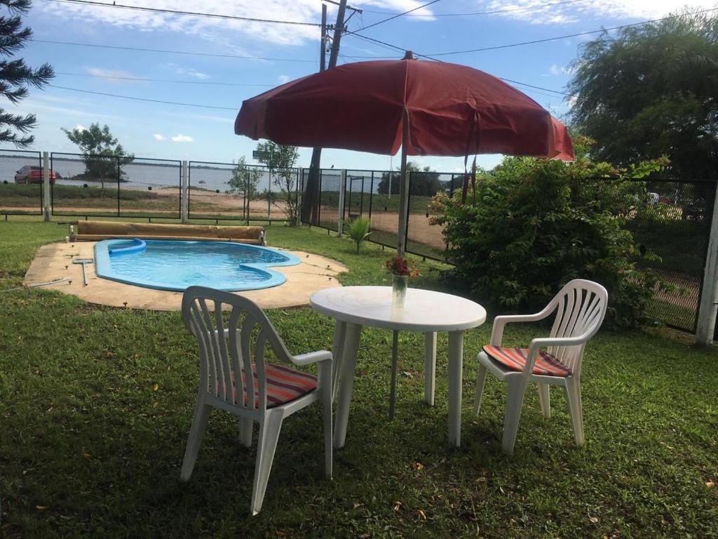 una mesa y sillas bajo una sombrilla junto a una piscina en LA ASCENSIÓN PASO DE LA PATRIA en Paso de la Patria