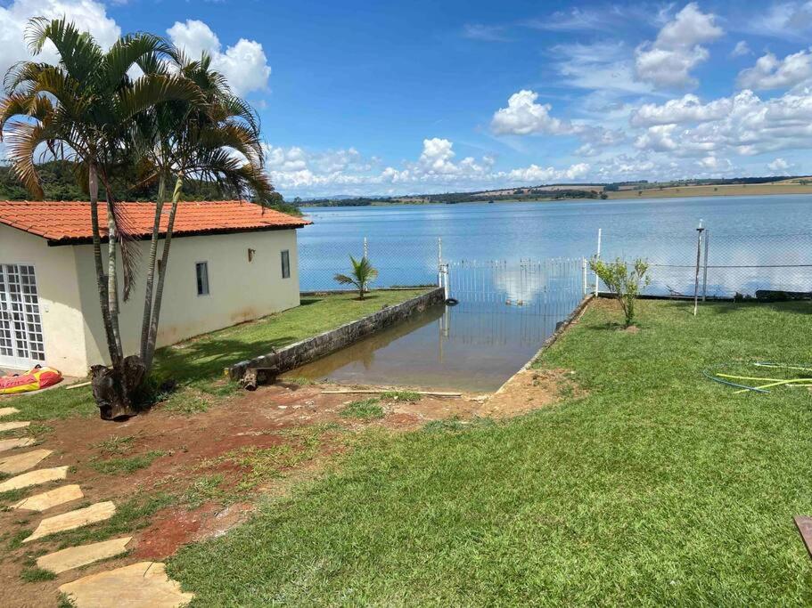une maison avec un palmier à côté d'une masse d'eau dans l'établissement Casa à beira lago de Furnas. (Pé na água), à Formiga