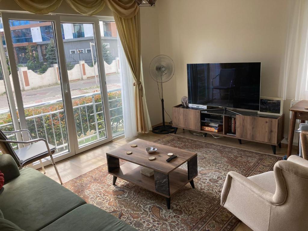 a living room with a couch and a tv and a table at Cozy Apartment in a Popular Neighborhood in Çorlu