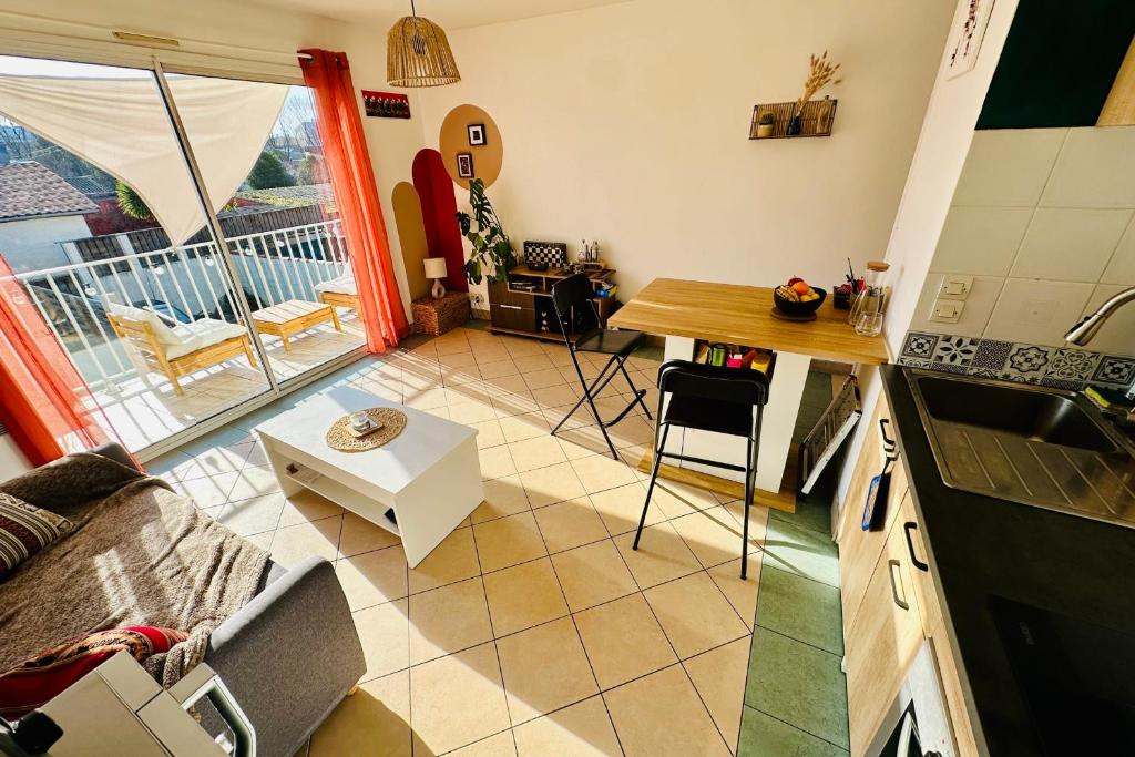 a kitchen and living room with a view of a balcony at Charming well-equipped apartment with wifi in Bordeaux