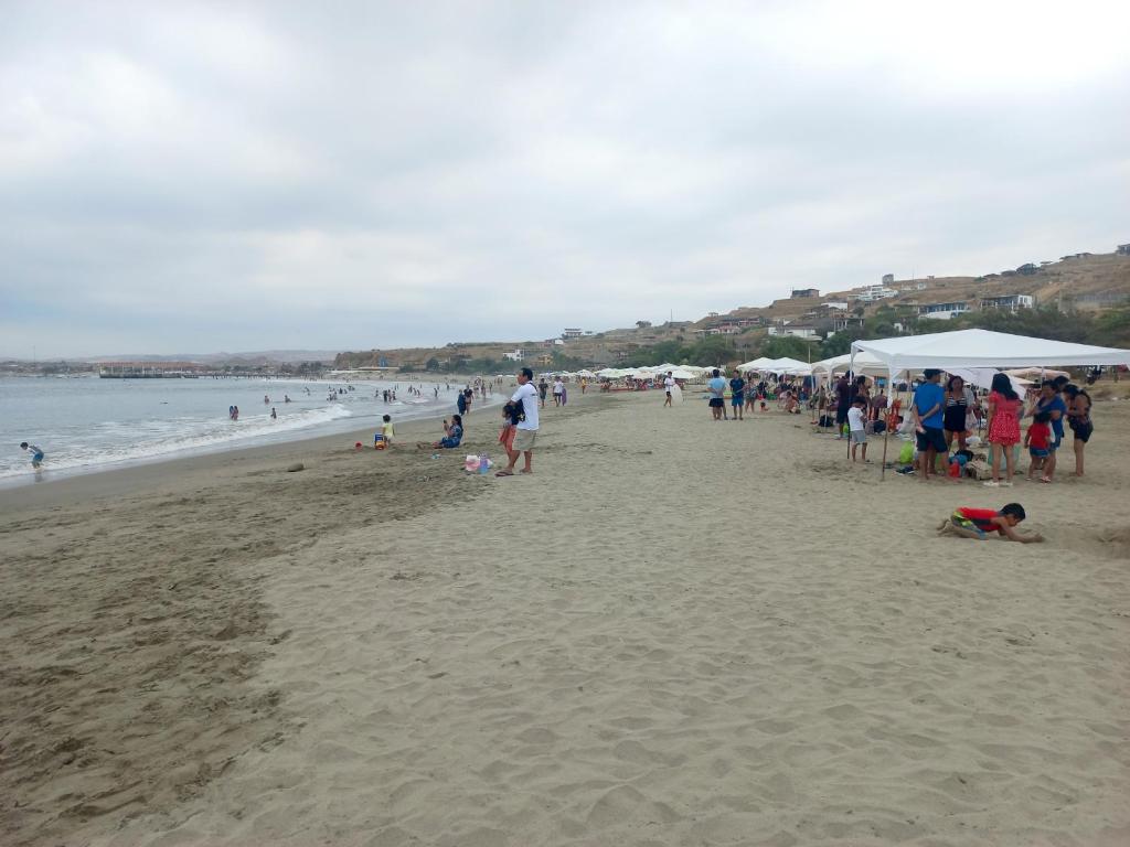 un grupo de personas de pie en una playa en Casa Entre Rocas y Veleros, en Los Órganos