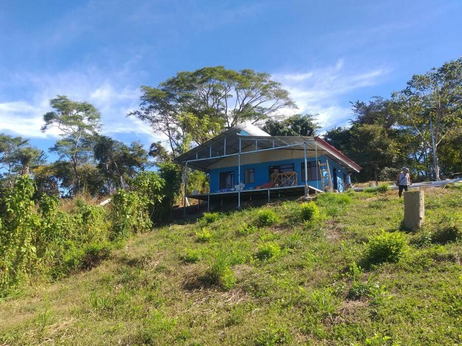 une maison bleue au sommet d'une colline herbeuse dans l'établissement Villa, KOCORU Casa de campo y playa, à Puntarenas