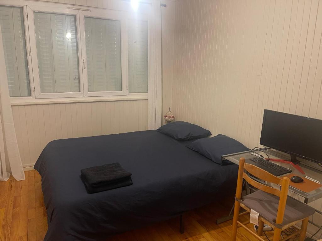 a bedroom with a bed and a desk with a computer at T4 spacieux tout confort &#47; parking gratuit in Grenoble