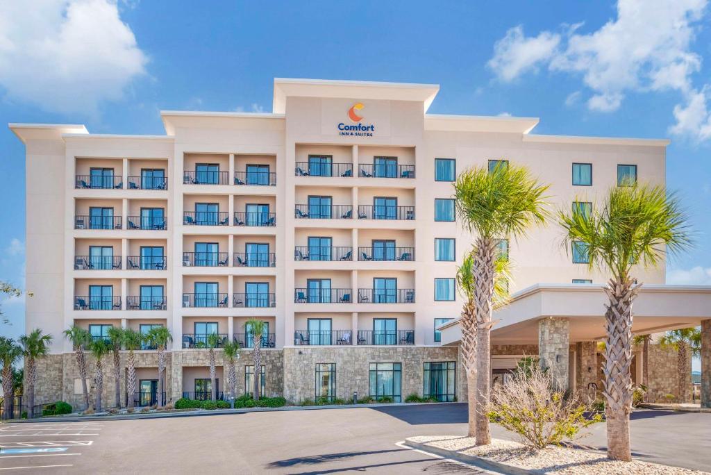 an exterior view of a hotel with palm trees at Comfort Inn & Suites Gulf Shores East Beach near Gulf State Park in Gulf Shores