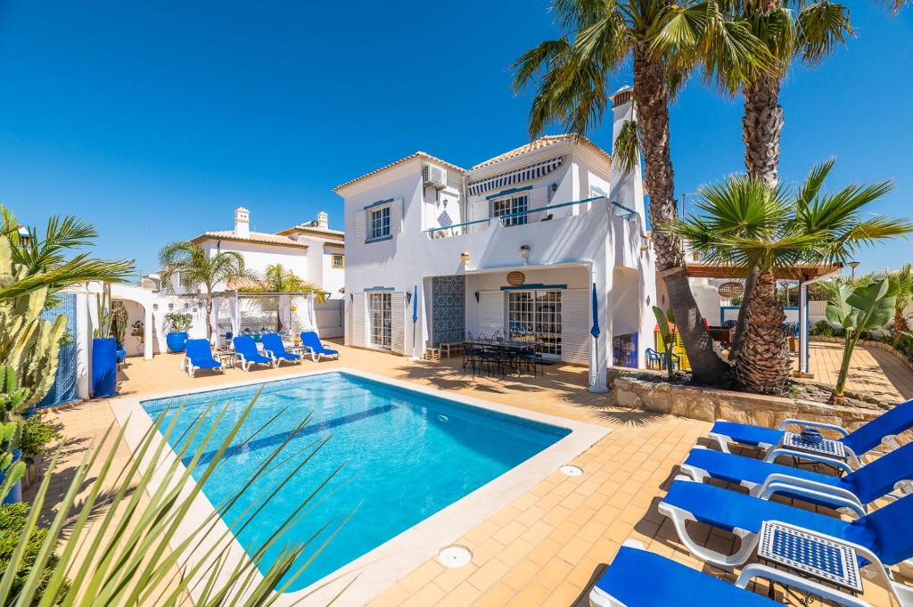 a villa with a swimming pool and palm trees at Villa Oasis Galé - Luxury Villa with private pool, AC, free wifi, 5 min from the beach in Albufeira