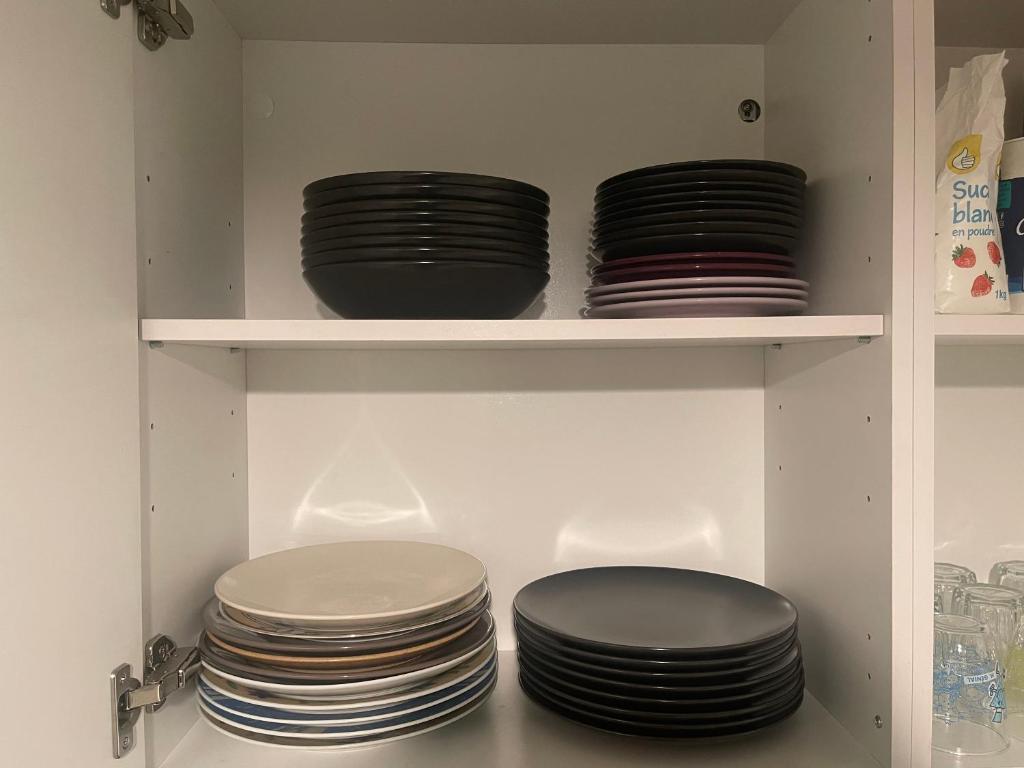 a cabinet filled with plates and bowls on shelves at T4 spacieux tout confort &#47; parking gratuit in Grenoble
