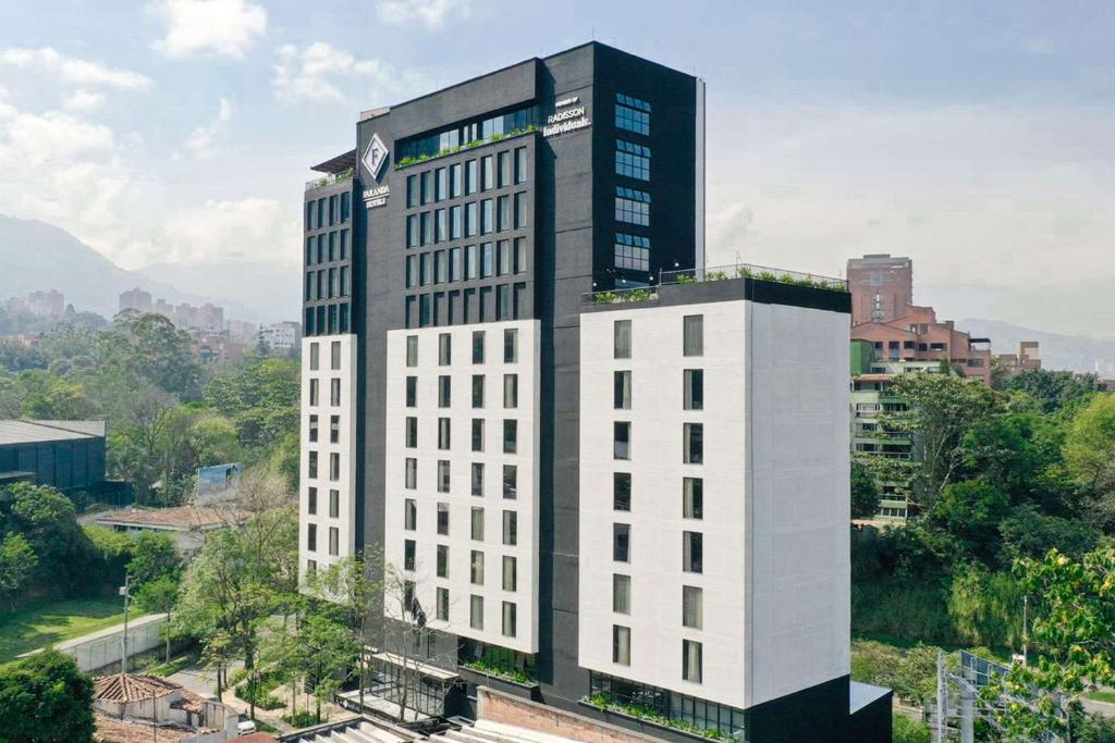 un edificio blanco alto con un reloj encima en Faranda Collection Medellin, a Member of Radisson Individuals en Medellín