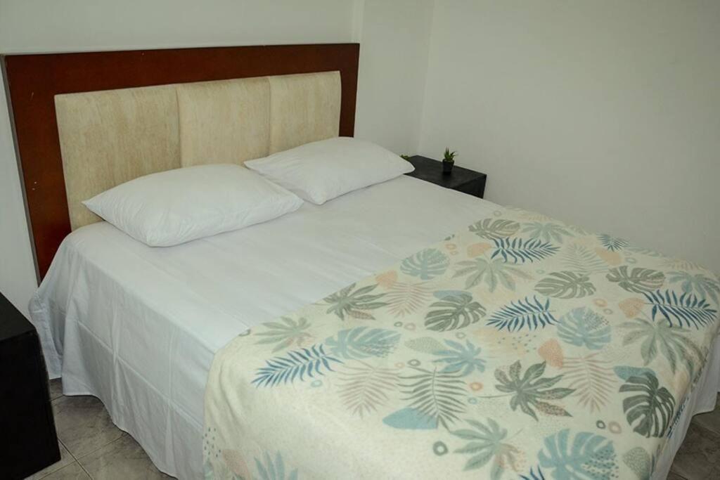 Schlafzimmer mit einem Bett mit einer weißen Bettdecke und einem Kissen in der Unterkunft Habitación privada – Super lugar in Bogotá