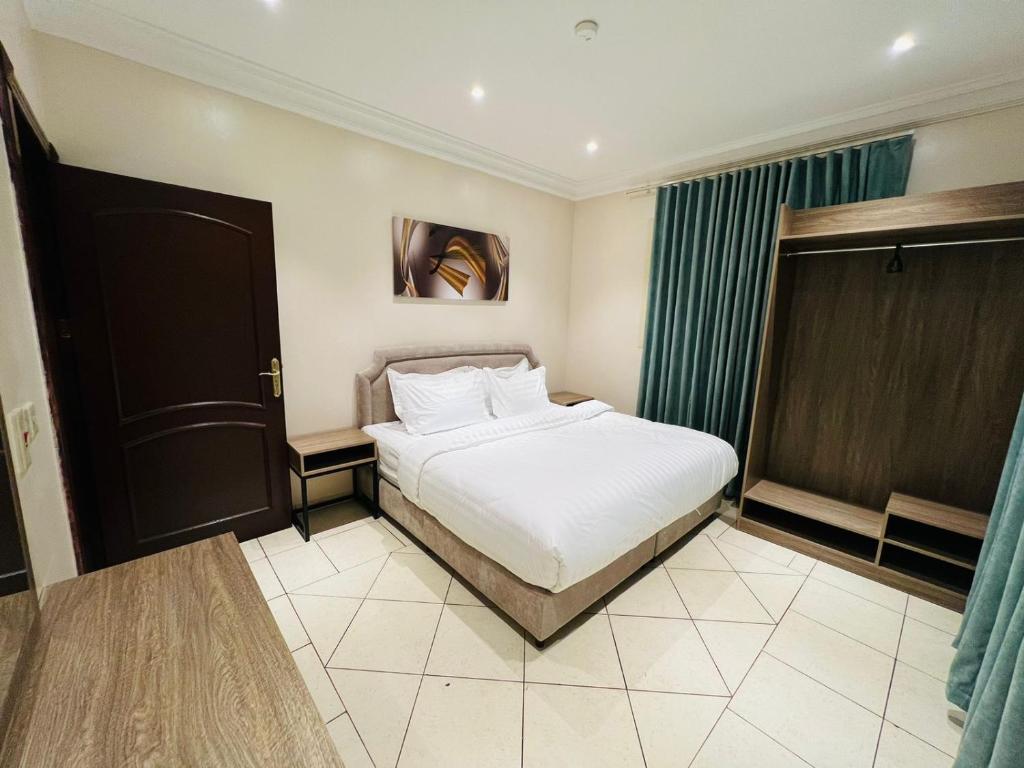 a bedroom with a white bed and a window at المهيدب للشقق المخدومة in Al Fuḑūl