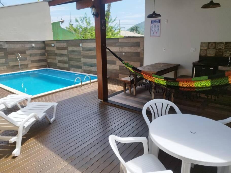 eine Terrasse mit einer Hängematte und einem Pool in der Unterkunft Casa com piscina em Zimbros in Bombinhas