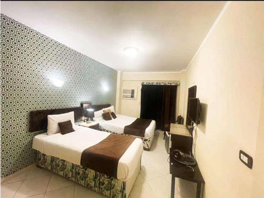 Habitación de hotel con 2 camas y TV en Golden Sun Hotel - Hurghada en Hurghada