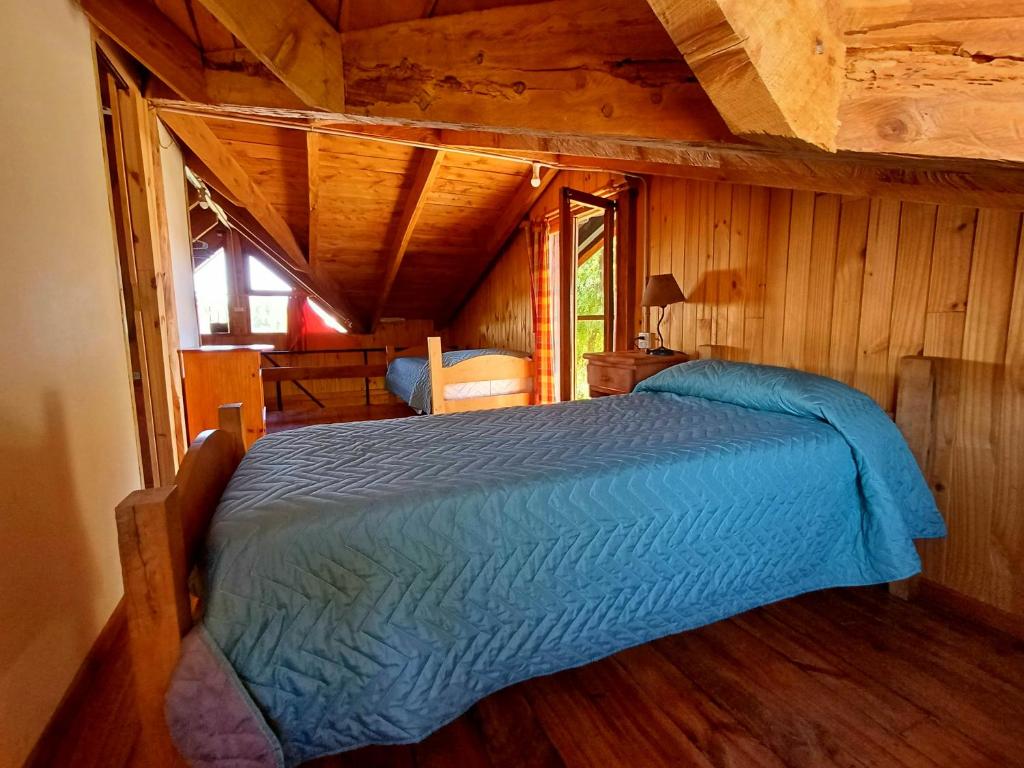 una camera da letto con un letto in una cabina di legno di Posada El Maiten a Trevelin