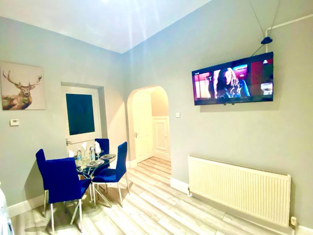 a living room with a table and a television on the wall at One Bedroom Ground Floor Apartment In Central London in London