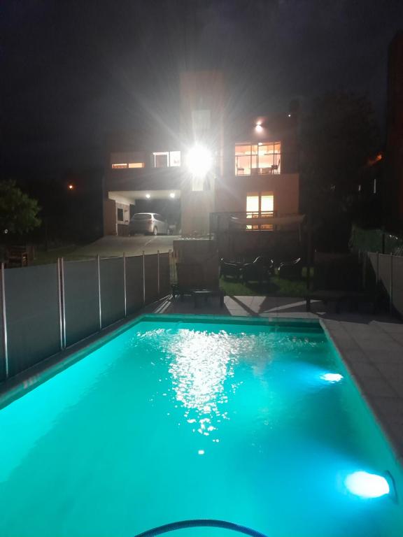 una piscina azul frente a una casa por la noche en La Allandesa en Cavalango