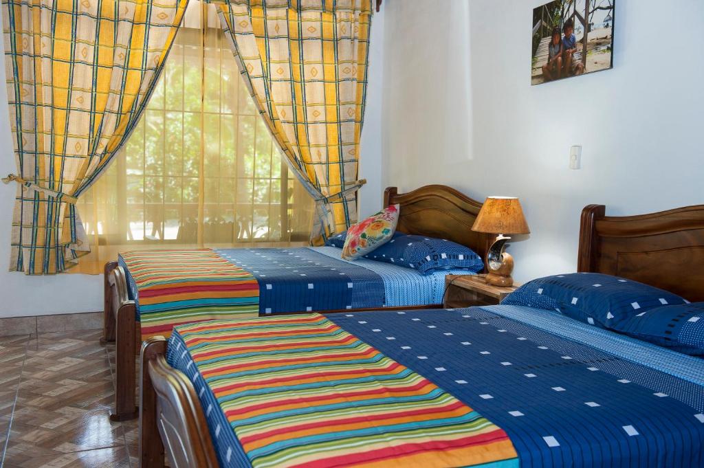 a bedroom with two beds and a window at Hotel Sunshine Caribe in Puerto Viejo