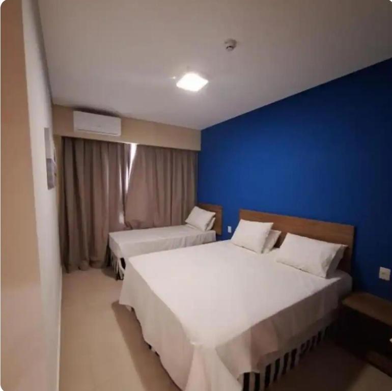 a bedroom with two beds and a blue wall at Quarto hotel Thermas São Pedro in São Pedro