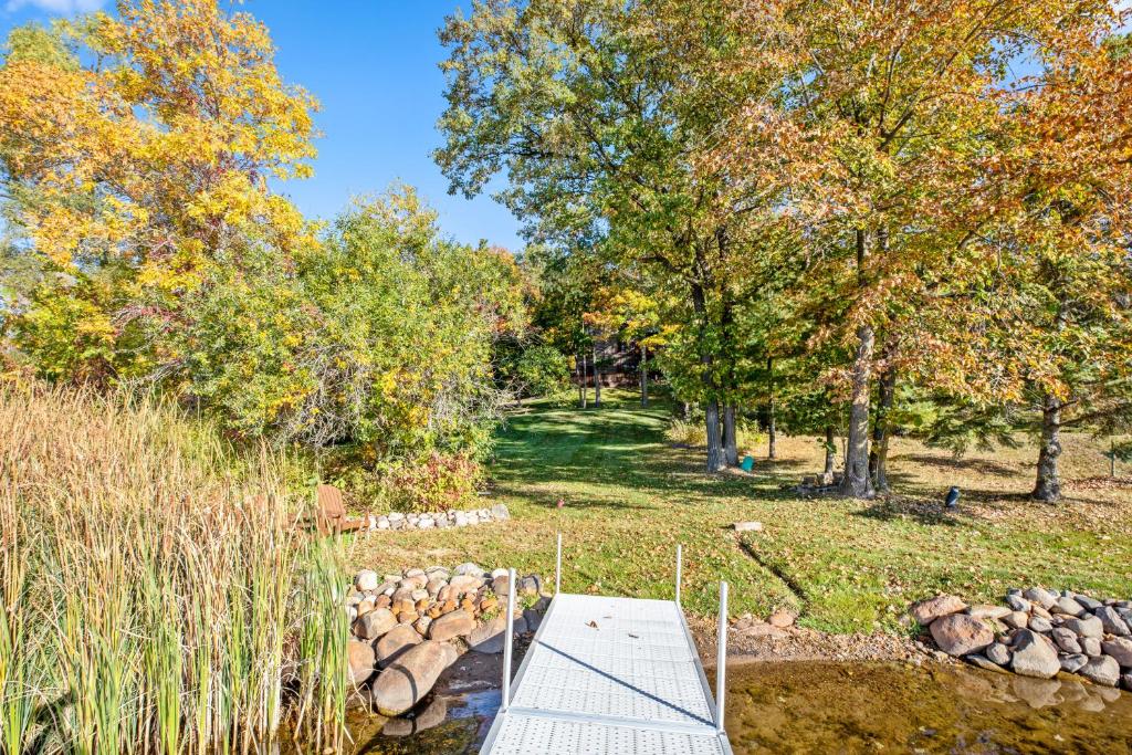 a bridge over a stream in a park with trees at The Loonstar Lodge On Rabbit Lake in Crosby