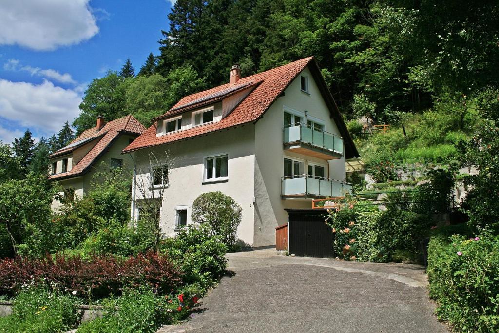 uma casa branca com um telhado vermelho numa colina em Haus am Waldrand em Triberg