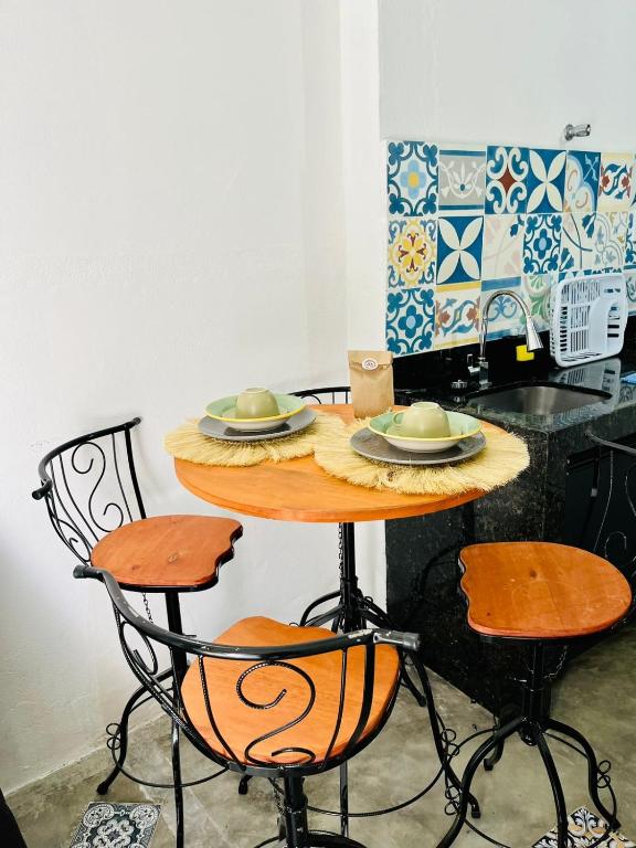 a table with two chairs and plates on it in a kitchen at CASINHA FLOR, no centro histórico!!! in Piranhas