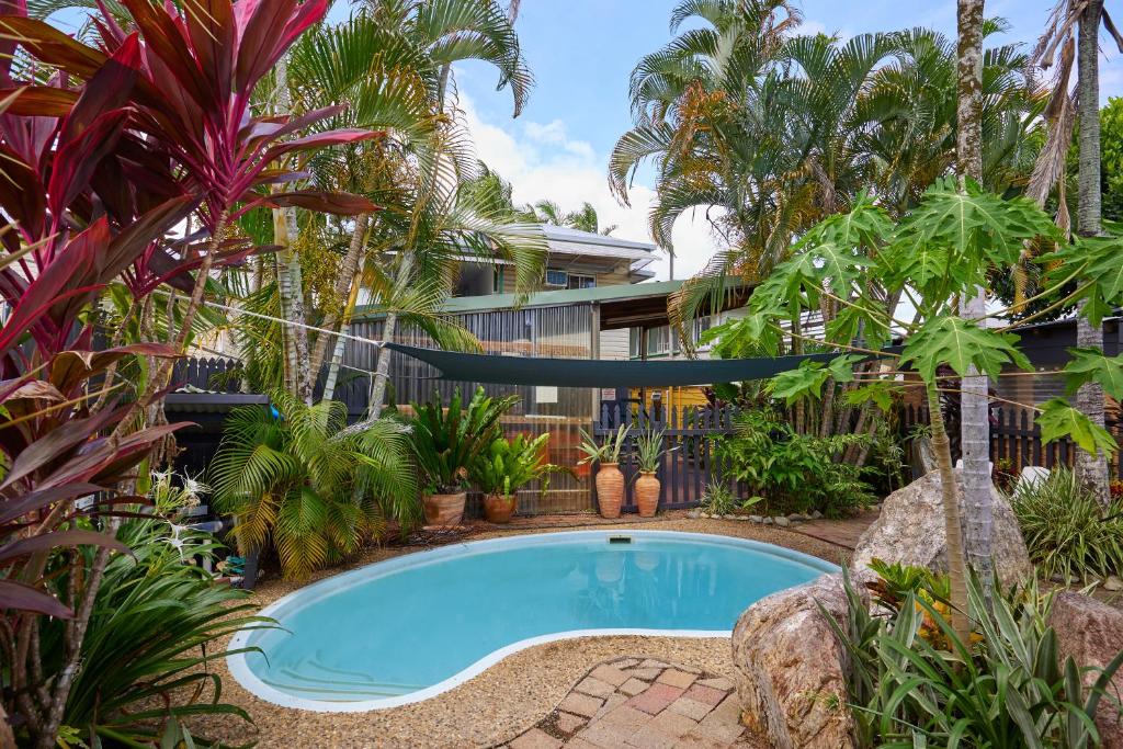 a swimming pool in front of a house with palm trees at Cairns City Backpackers Hostel in Cairns
