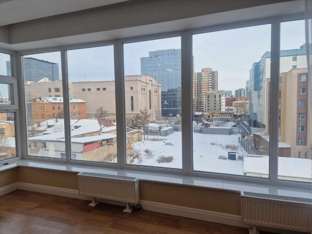 een groot raam met uitzicht op een besneeuwde stad bij Deegii's apartment in Ulaanbaatar