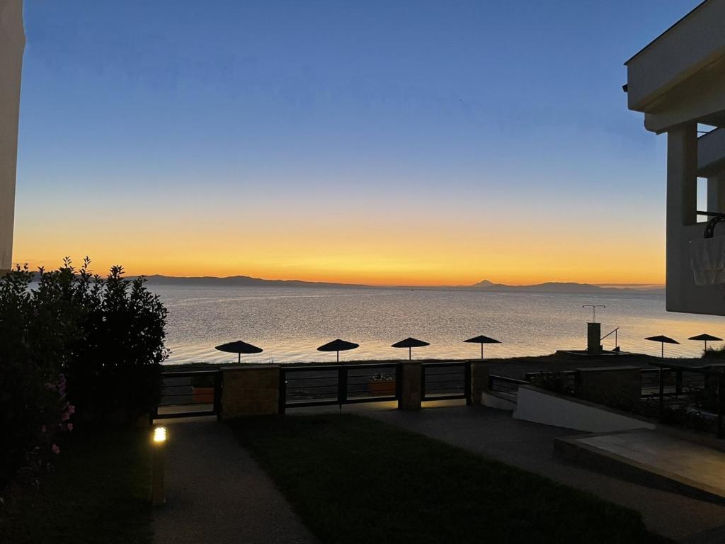 Blick auf das Meer bei Sonnenuntergang mit Sonnenschirmen in der Unterkunft Elpiniki Luxury Apartments in Nea Potidaea