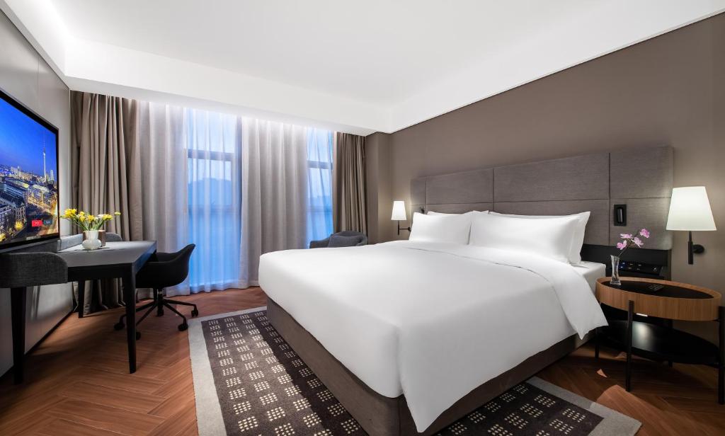 um quarto de hotel com uma grande cama branca e uma secretária em Intercity Wuhan Guanshan Avenue em Wuhan