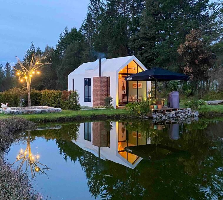 a small white house with its reflection in a pond at Casa con vista a las montañas in Quito