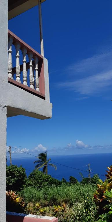 einen Balkon eines Hauses mit Meerblick in der Unterkunft "SunRise Inn" Nature Island Dominica in Penville