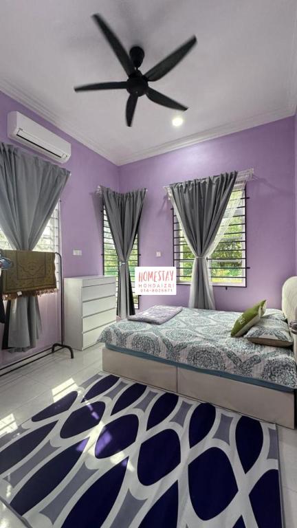 a purple bedroom with a bed and a ceiling fan at Homestay Mohd Aizri Bukit Gading in Tanah Merah