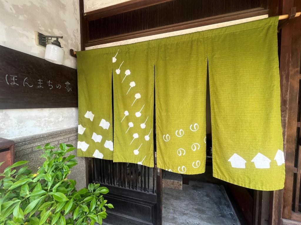 una cortina verde en una puerta con una planta en （一棟貸切）町家体験ゲストハウス「ほんまちの家」〜高岡市の伝統的な古民家～, en Yokota
