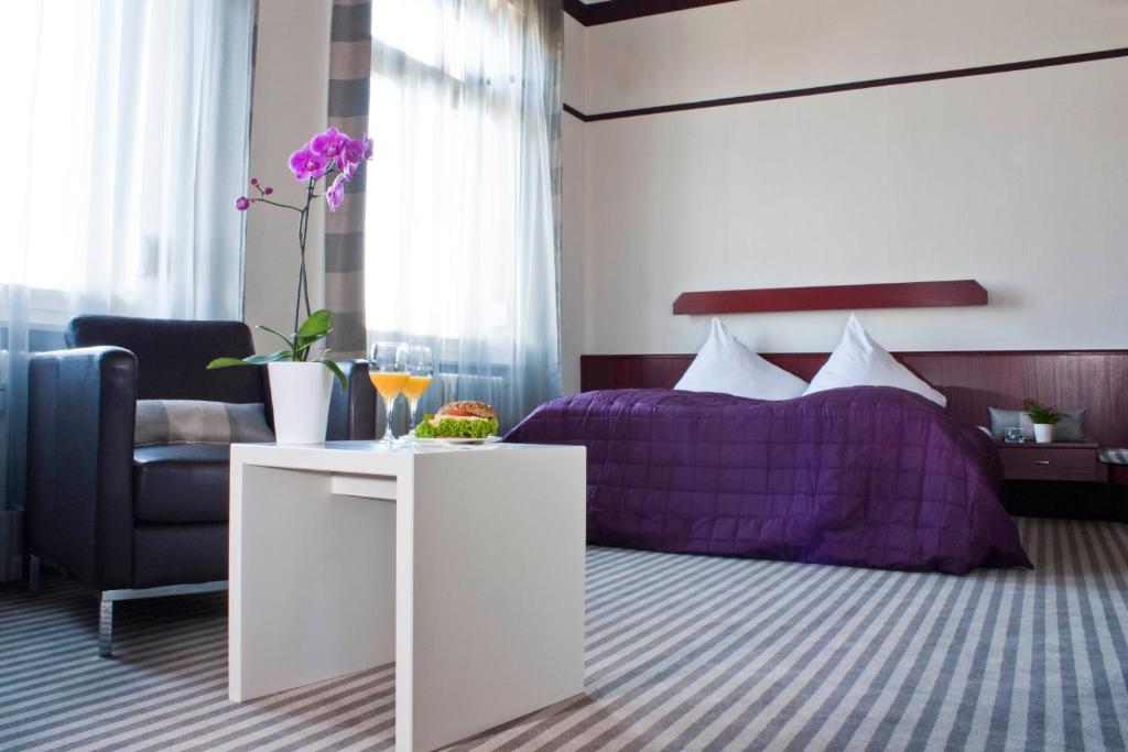 ein Schlafzimmer mit einem lila Bett und einem Stuhl in der Unterkunft Hotel Neuer Karlshof in Baden-Baden