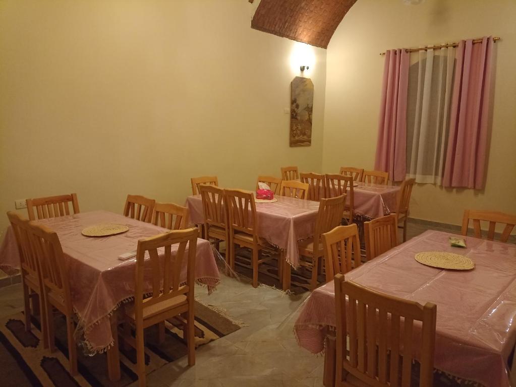 uma sala de jantar com mesas e cadeiras com toalhas de mesa cor-de-rosa em Rahala Safari Hotel em Qasr Farafra