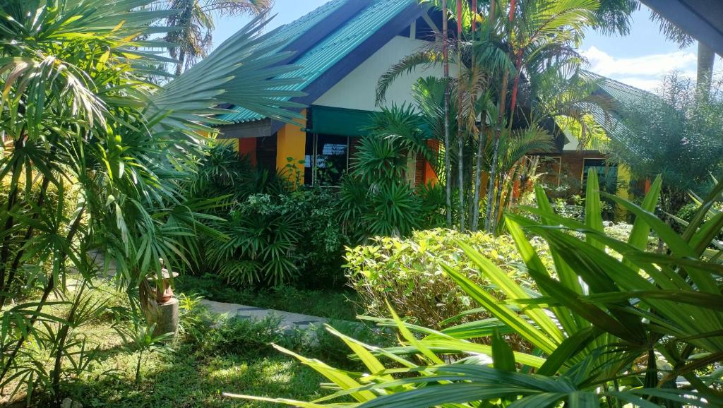 einen Garten vor einem Gebäude mit Palmen in der Unterkunft Sanuk Bungalow in Khao Lak