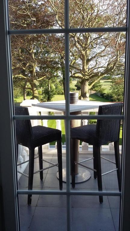 uma vista para uma mesa e cadeiras através de uma janela em Le Petit Chateau Vaartdijk em Leffinge