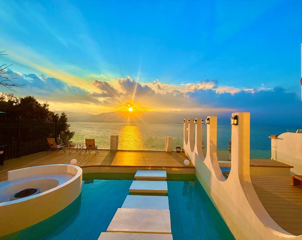 a swimming pool with a sunset in the background at Dali Luyu Cliff Seaview Inn in Dali