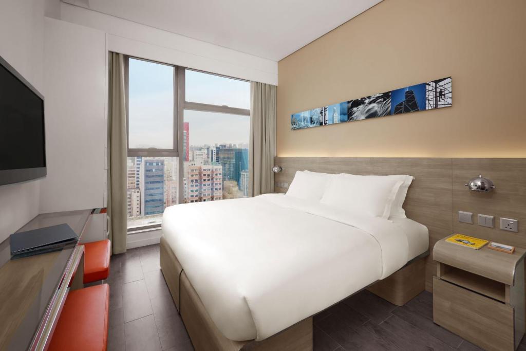 una camera d'albergo con un grande letto e una grande finestra di Lodgewood by Nina Hospitality Mong Kok a Hong Kong