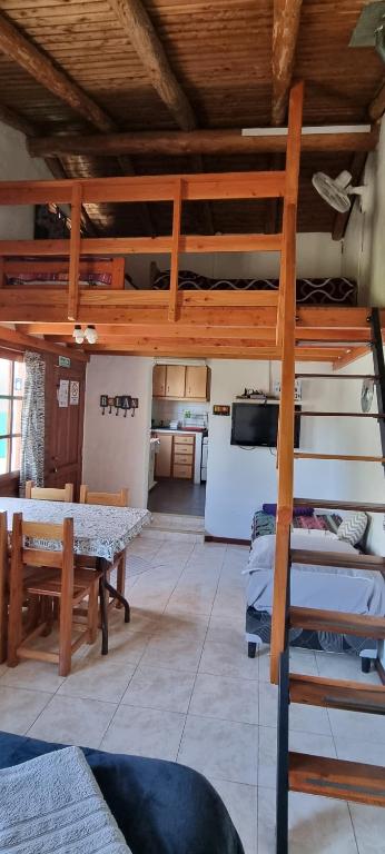 um quarto com uma cama alta, uma mesa e uma cozinha em Casa Sur em El Bolsón