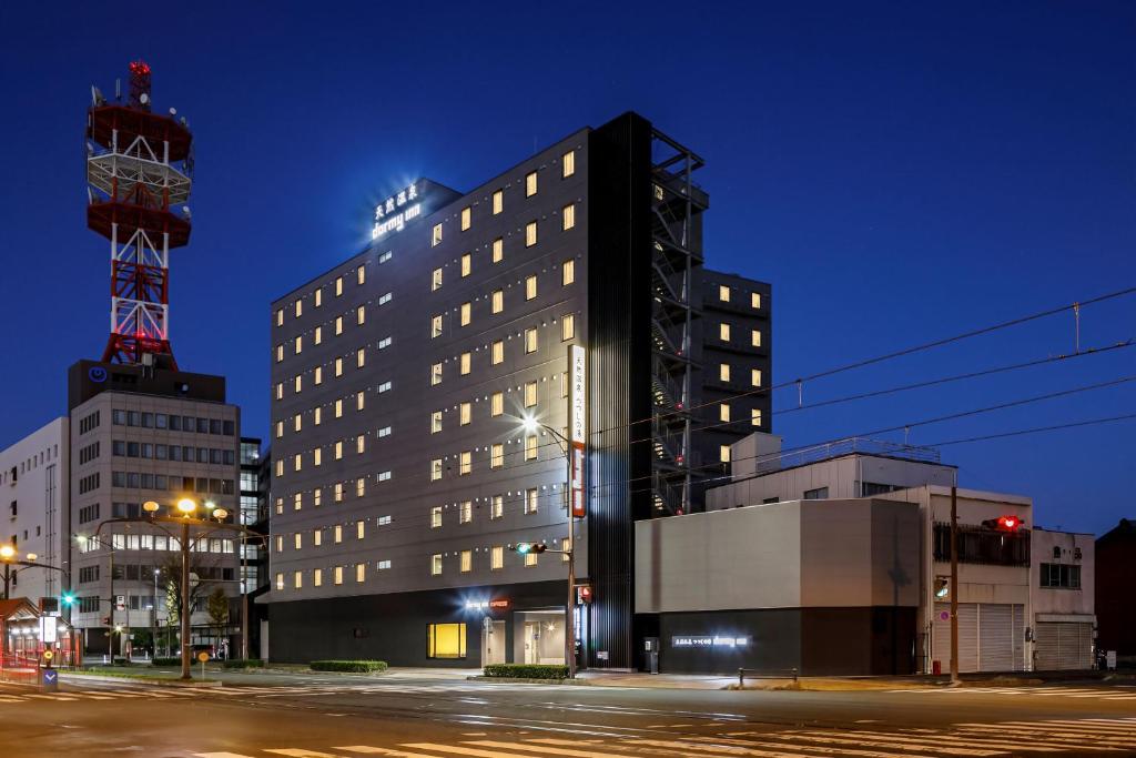 a tall black building on a city street at night at Dormy Inn Express Toyohashi in Toyohashi