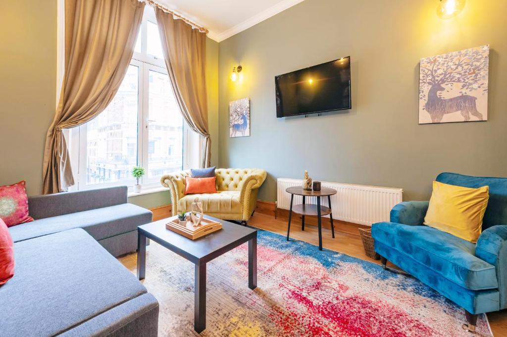 a living room with a couch and chairs and a tv at 2 Bedroom in Center of London in London