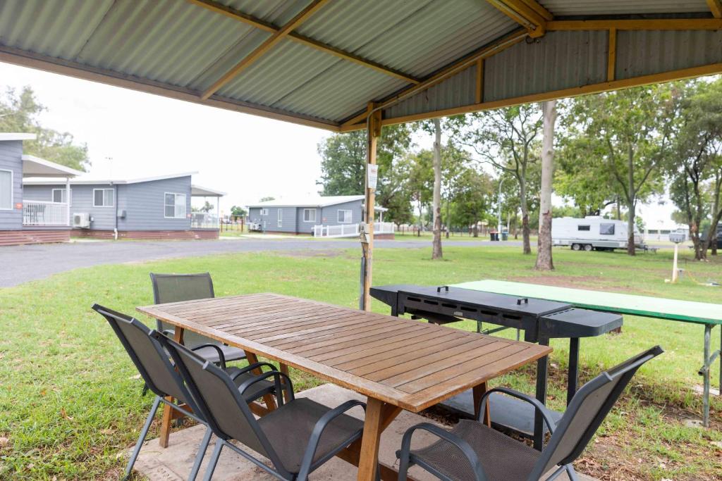 a wooden table and chairs under a pavilion with a table and a ping p at Coonamble Riverside Caravan Park in Coonamble