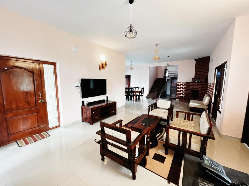 ein Wohnzimmer mit einem Tisch und einem TV in der Unterkunft Hill Town Villa in Udagamandalam