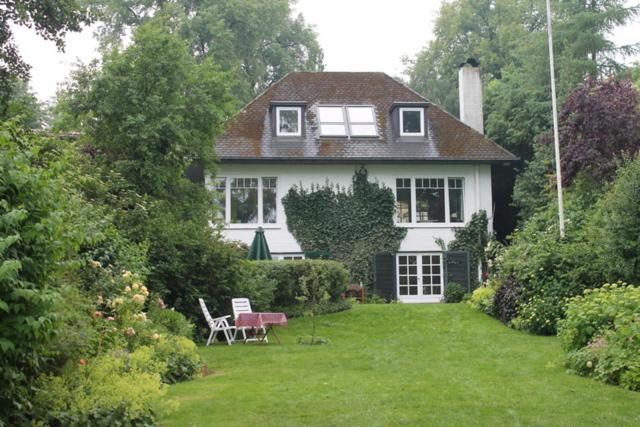 uma casa branca com um quintal com duas cadeiras em Seeblick em Westensee