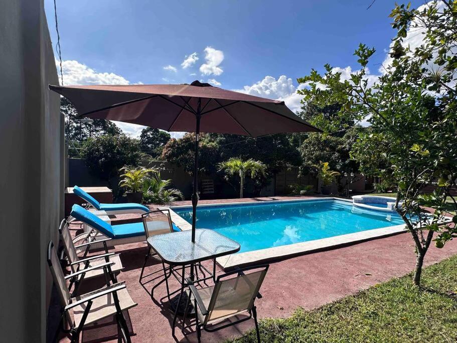 a table with an umbrella next to a swimming pool at Payes Home in Siguatepeque