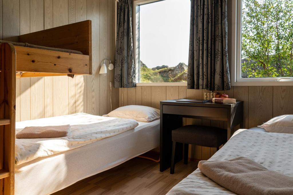 a bedroom with two beds and a desk and a window at Vogar Travel Service in Myvatn